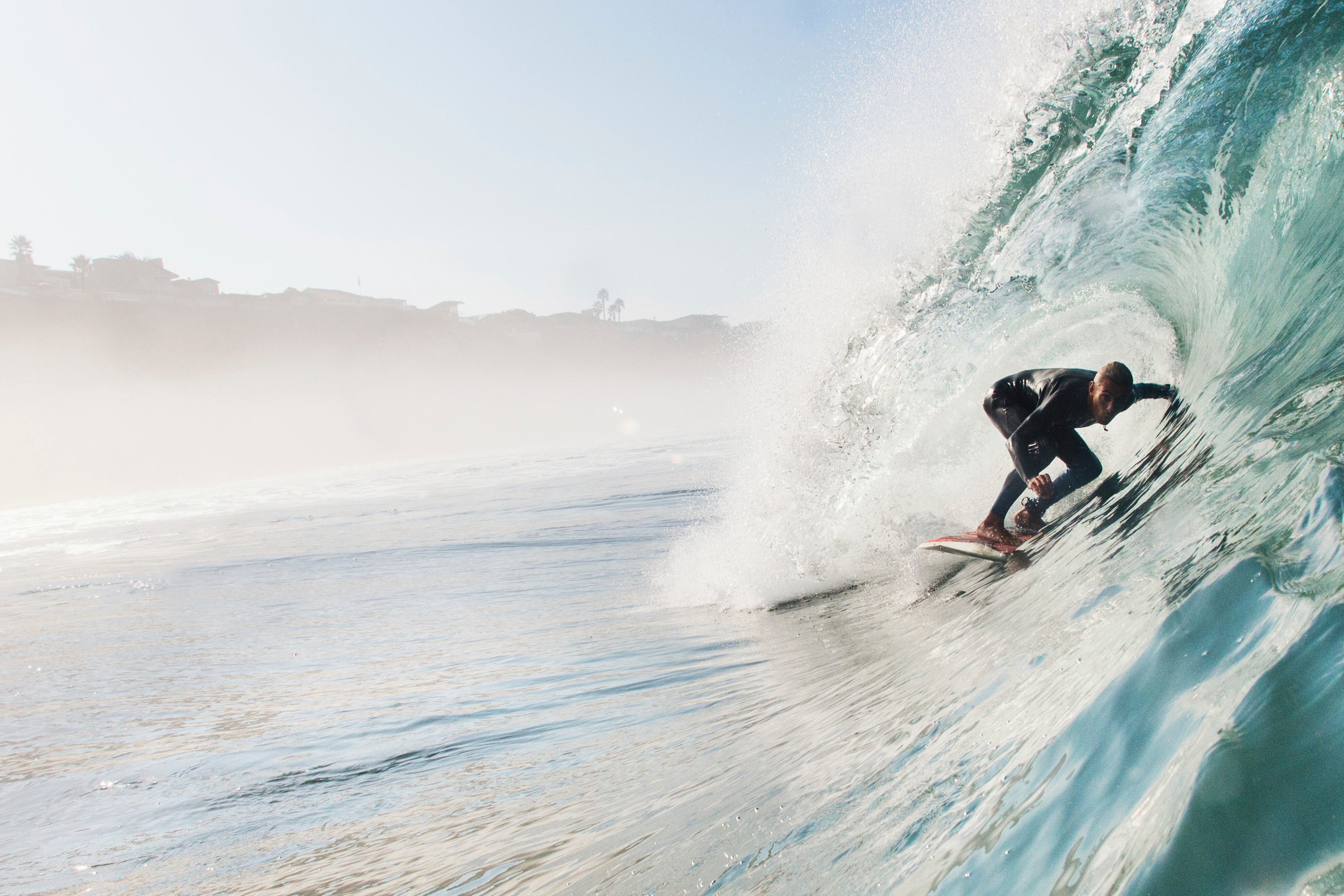 Person surfing a large wave in the ocean off the coast of San Diego